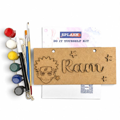 A personalized wooden nameplate kit on a white background, featuring a natural brown wood plaque engraved with a Naruto character and the name 'Ram', accompanied by paint pots, paintbrushes, and a 'SPLASH' branded instruction card.