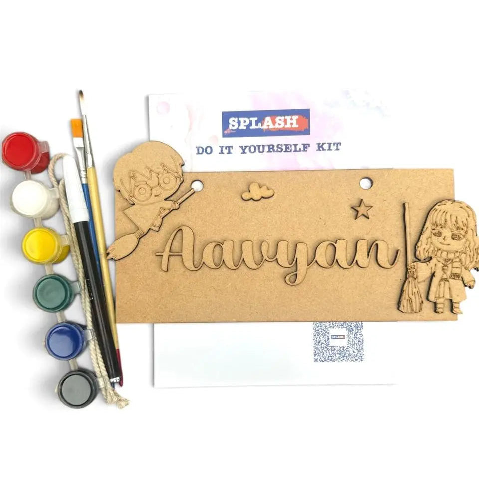 A DIY wooden name painting kit for kids, featuring a personalized wooden plaque with a cutout name 'Aavyan', cartoon girl and boy designs, a paint palette with six paint wells, and two paintbrushes on a white background.
