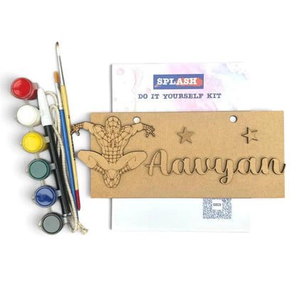 A DIY canvas painting kit labeled 'SPLASH DO IT YOURSELF KIT' with a wooden Spider-Man cutout, a name plate reading 'Aavyan', paint pots, and paintbrushes on a white background.