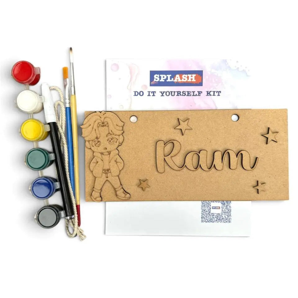A DIY acrylic art kit by Splash featuring a personalized name 'Ram' engraved on a brown cardboard plaque, accompanied by a paint palette, paint tubes, and drawing tools on a white background.