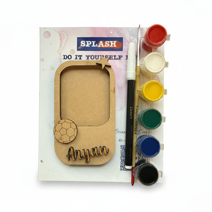 Personalized laser-cut wooden name plaque kit with a soccer theme, shown with a paint palette, paint brush, and printed backing card on a white background.
