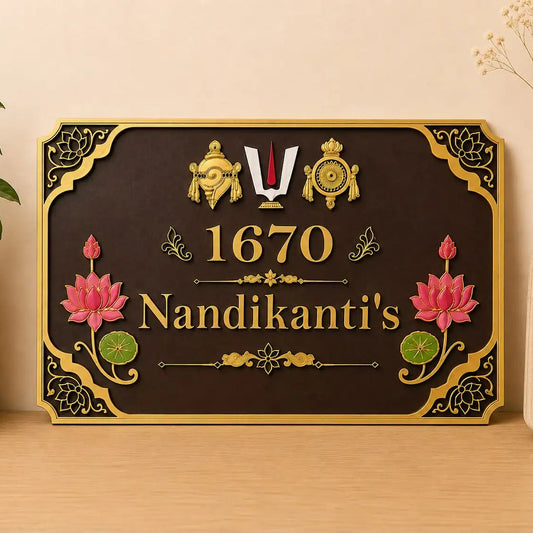 A decorative rectangular wall sign with a dark brown background and ornate gold border, featuring the text '1670 Nandikanti's' with pink lotus flowers and gold decorative motifs. The sign is displayed on a light wood surface against a beige wall, flanked by a potted plant on the left and a vase with dried stems on the right.