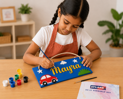 Child painting a nameplate with 'Mayra' on a wooden table.