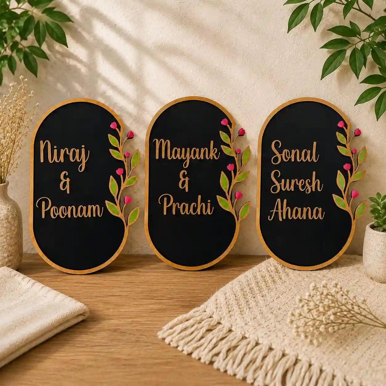 Three decorative nameplates with names and floral designs on a wooden surface.