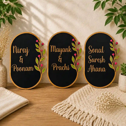 Three decorative nameplates with names and floral designs on a wooden surface.