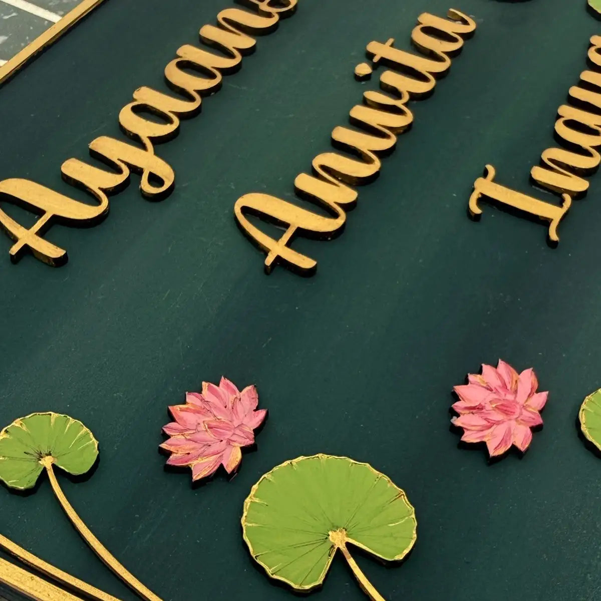 Gold name plates with pink flowers and green leaves on a dark green background