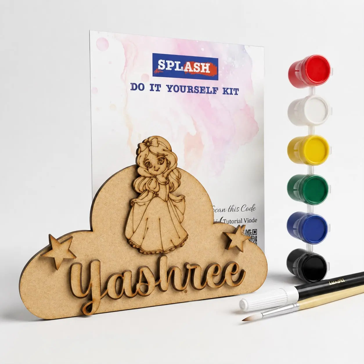 Personalized wooden name art kit with a laser-cut cloud plaque reading 'Yashree' and a cartoon girl, shown with a printed instruction card, six small paint pots, and two paintbrushes on a light gray background.