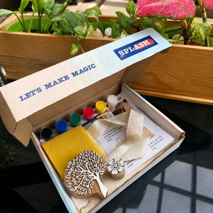 Open box with art supplies and 'Splash' branding, set against a garden background.